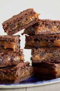 a stack of chocolate brownies with caramel toppings on a blue and white plate