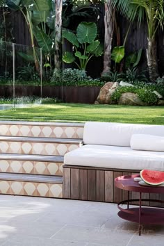 a white couch sitting on top of a wooden bench next to a lush green field