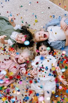 three children laying on the floor surrounded by confetti