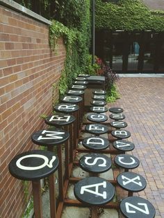 a row of black and white numbers sitting on top of a brick sidewalk next to a building