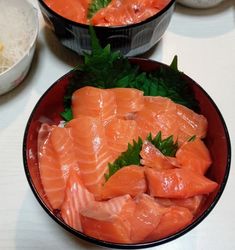 two bowls filled with salmon on top of a table