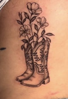 a tattoo with boots and flowers on the back of a woman's stomach,