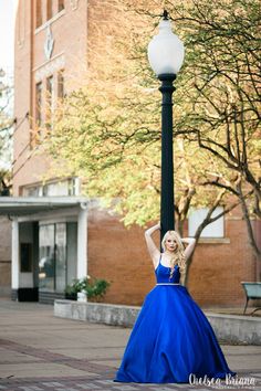 a woman in a long blue dress standing next to a lamp post