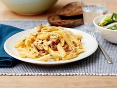 a white plate topped with pasta and meat next to a bowl of broccoli