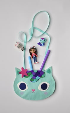 a doll is sitting on top of a cat mask with other items around it and tied to the side