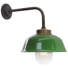 a green wall light with an old fashioned bulb on the side and a white background