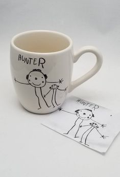 a white coffee cup with a drawing on it next to a note that says hunter