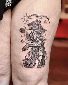 a black and white tattoo on the leg of a woman's thigh with a lion