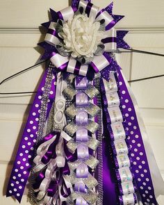 a purple and white bow with flowers on the top is attached to a door hanger