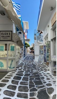 an empty street with shops and flags on the buildings in the background is a blue sky