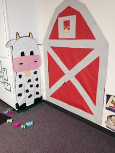 a cow standing in front of a barn door decorated with construction paper and cut outs