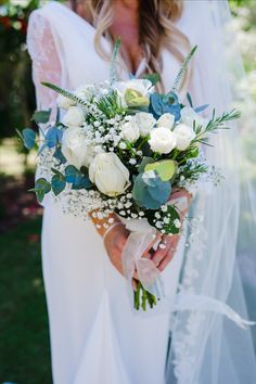 a bride holding a bouquet of white and blue flowers