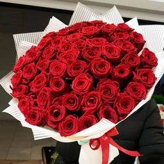 a woman holding a bouquet of red roses