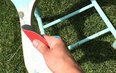 a person holding a pair of scissors in their hand next to a chair on the grass