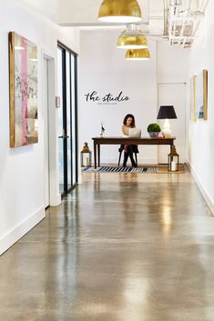 a woman is sitting at a desk in an office with the name she studio on the wall