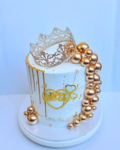 a white cake with gold decorations and a crown on top