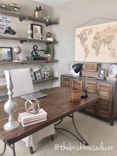 a home office with desk, bookshelf and map on the wall above it