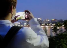 a man is taking a photo with his cell phone in front of the city lights