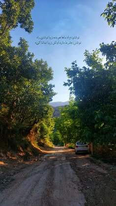 a car is parked on the side of a dirt road in front of some trees