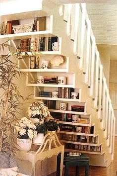 a living room filled with lots of furniture and bookshelves next to a stair case