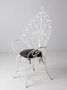 a white metal chair with a black cushion on it's back and armrests