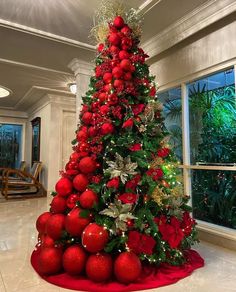 a christmas tree with red balls and greenery on it in the middle of a room