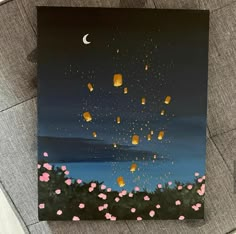 a painting on the ground with pink flowers and lanterns flying in the sky