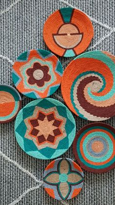 several woven bowls are sitting on the floor next to each other and one has an orange, brown, blue, and green design