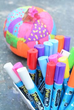 some markers and pens are sitting in a container next to an easter egg on the ground