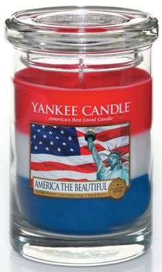 yankee candle with the statue of liberty on it and an american flag in the background