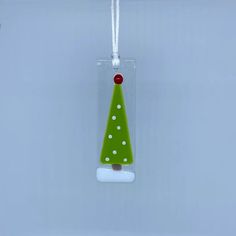 a glass ornament with a green christmas tree on it's side hanging from a cord