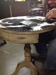 a man is working on an old table with cow hides and leather trimming