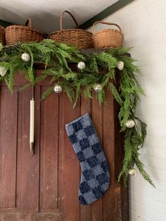 a christmas stocking hanging on a door with greenery and stockings hung from it