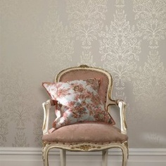 an old chair with a pillow on it in front of a wallpapered room