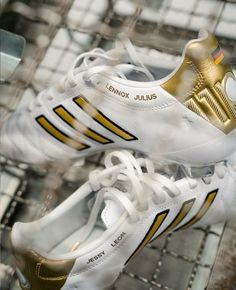 a pair of white and gold adidas soccer cleats sitting on top of each other