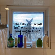 a bathroom window with soap bottles on it and a deer looking out the window in the background