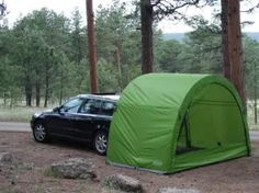 a car parked next to a tent in the woods