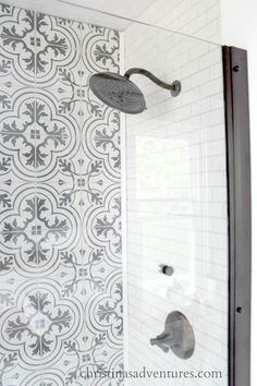 a bathroom with white and black tile on the walls, shower head and hand held faucet