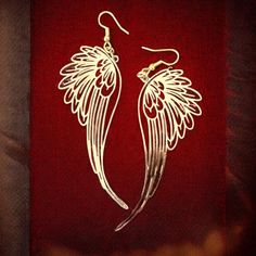 two pairs of angel wings are shown on a red background with gold earwires