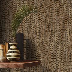 a vase sitting on top of a wooden table next to a wallpapered background