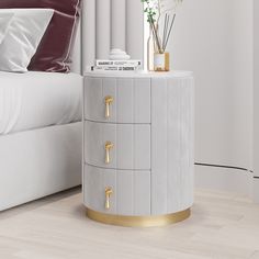 a white and gold side table with flowers on it next to a king size bed