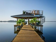 a dock with potted plants on it next to the water