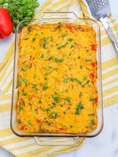 a casserole dish with cheese, tomatoes and parsley next to a fork