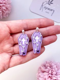 the purple earrings are decorated with flowers and cross charms on it's earwires