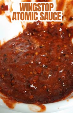 a white bowl filled with red sauce on top of a wooden table and the words wingstop atomic sauce above it