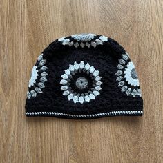 a black and white crocheted hat sitting on top of a wooden floor