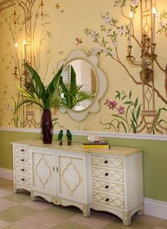 a white dresser sitting next to a mirror on top of a wall