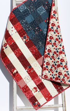 two red, white and blue quilts sitting on top of an old wooden chair