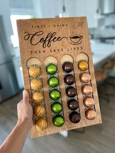 a person holding up a wooden sign with different types of candies in it and the words first drink coffee then save lives