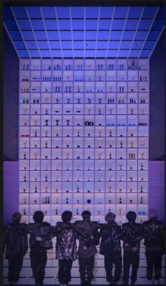 four people standing in front of a wall with letters on it and numbers written all over them